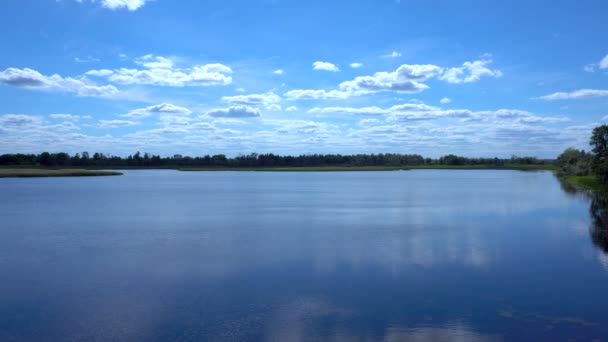 Nuvens são refletidas no lago. Vista do lago na grama distante e nuvens — Vídeo de Stock