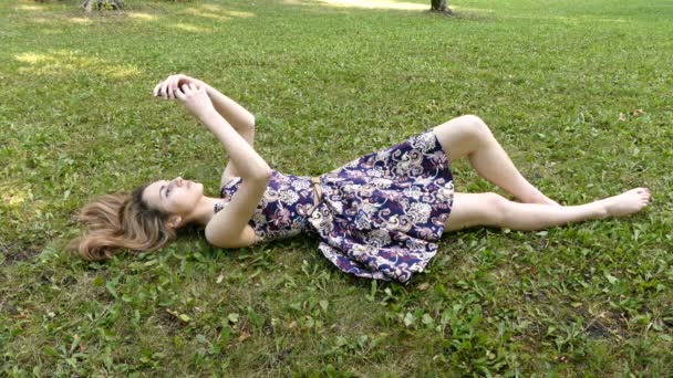 Девушка с телефоном на траве — стоковое видео