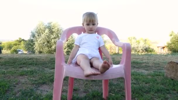 Küçük bir kız sandalyede oturuyor. — Stok video