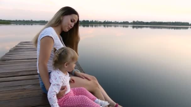 Мать и дочь сидят у озера — стоковое видео