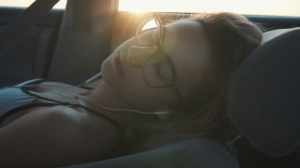 Flicka med hörlurar sover i bilen — Stockvideo