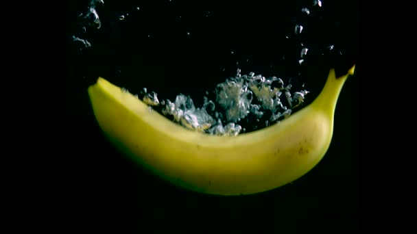 Banane fällt in Zeitlupe ins Wasser. isoliert auf schwarzem Hintergrund mit Alpha. Nahsicht — Stockvideo