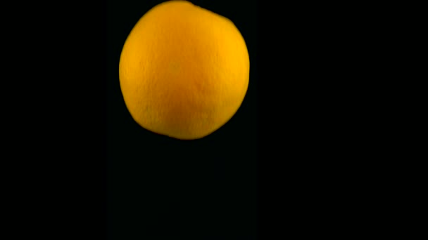 Апельсин падает в воду в замедленной съемке. Изолирован на черном фоне с альфой. Закрыть вид — стоковое видео