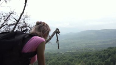 Bir turist uçurumun altındaki ormana bakıyor.