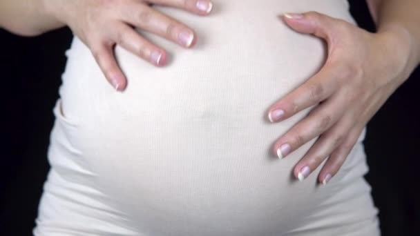 Mujer embarazada acariciando su gran vientre con sus manos. Mujer con una camiseta ligera — Vídeo de stock