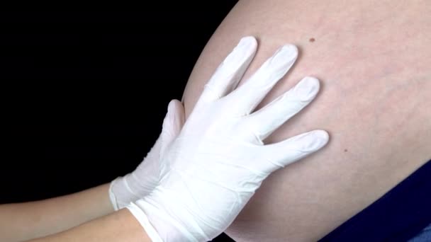 Лікар торкається живота вагітної жінки. Молода жінка з великим животом на огляді у лікаря — стокове відео