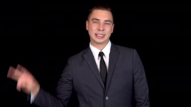 Young businessman shows victory sign with his hand. Man in a black suit on a black background — Stock Video