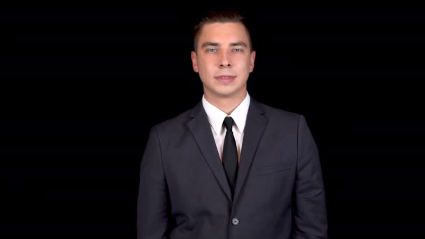 Ein junger Geschäftsmann nickt zustimmend. Mann im schwarzen Anzug auf schwarzem Hintergrund — Stockvideo