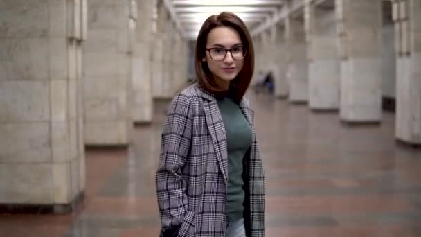 У метро ходить молода жінка. Дівчина в пальто і окулярах — стокове відео