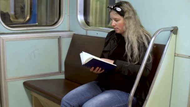 Una mujer embarazada está leyendo un libro en un tren subterráneo. Antiguo vagón de tren del metro — Vídeo de stock