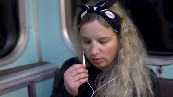 Una mujer embarazada está hablando por teléfono a través de auriculares a un tren subterráneo. Antiguo vagón de tren del metro — Vídeo de stock