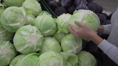 Bir kız markette lahana seçiyor.