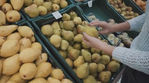 En flicka väljer päron på marknaden — Stockvideo