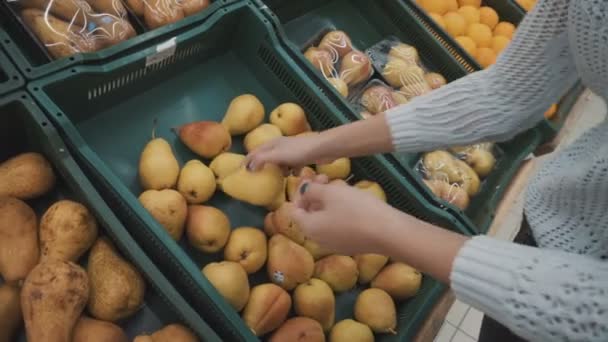 Девушка выбирает груши на рынке — стоковое видео