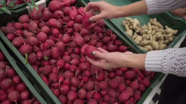 Una chica elige los rábanos en el mercado — Vídeo de stock