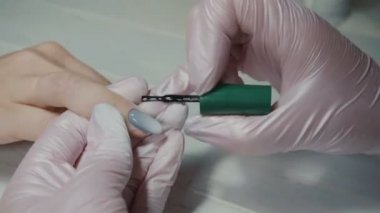 Manikürcü bir kızın tırnaklarını boyuyor.