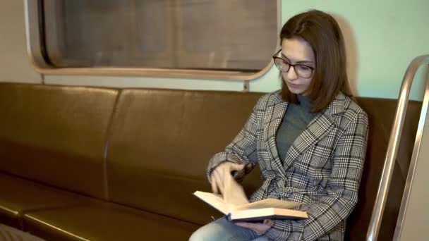 Una joven está leyendo un libro en un tren subterráneo. Viejo vagón de metro — Vídeo de stock