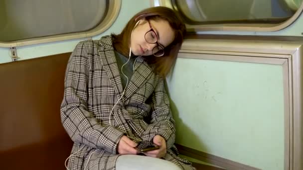 Una giovane donna si addormentò su un treno della metropolitana. Ragazza con le cuffie nelle orecchie. Vecchia metropolitana — Video Stock