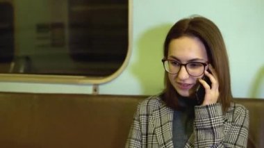 Metroda genç bir kadın telefonda konuşuyor. Eski metro vagonu