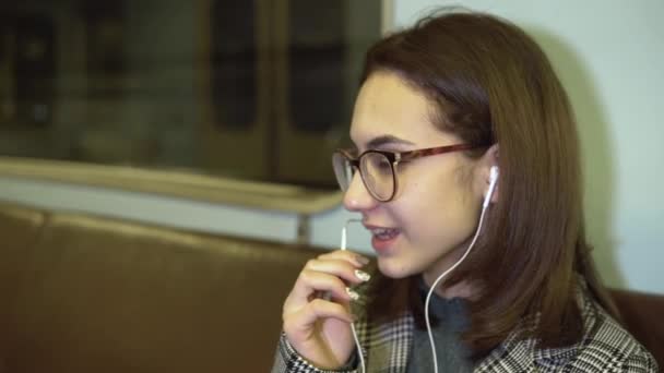 Een jonge vrouw is aan het telefoneren via een koptelefoon in een metro. Oude metro auto — Stockvideo