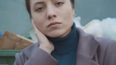 Kız çöpün arka planında duruyor. Yüzünü kapat.