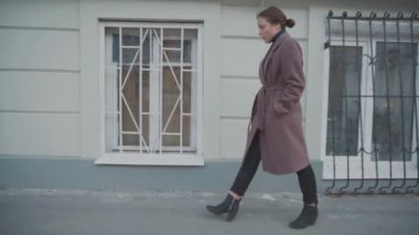 Leylak paltolu kız eski şehrin sokaklarında yürüyor.