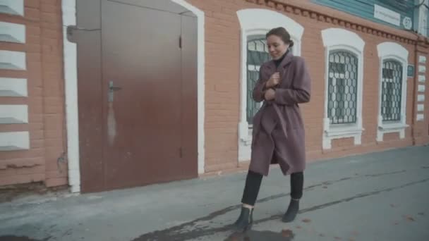 Το κορίτσι με το λιλά παλτό περπατά στους δρόμους της παλιάς πόλης — Αρχείο Βίντεο