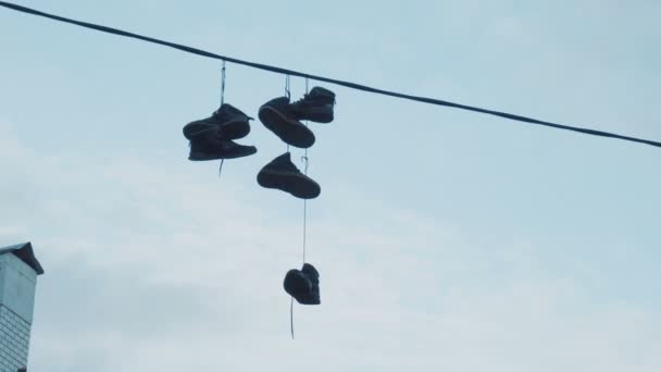 Trois paires de baskets suspendues à des fils électriques à une hauteur de neuf mètres sur la rue de la ville — Video