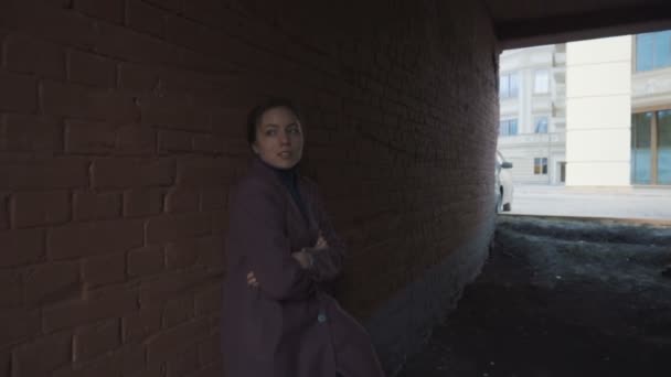 Das Mädchen im Mantel steht im Tunnel an der Wand — Stockvideo
