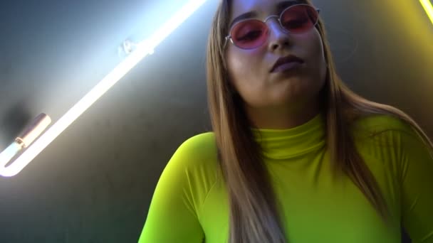 Fashionable girl on the background of a neon lapms clouse-up — Stock Video