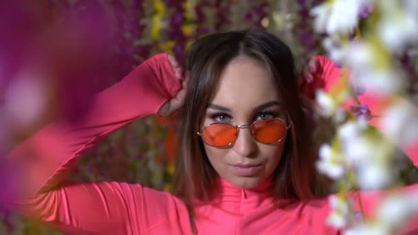 Модная девушка в очках среди цветов — стоковое видео