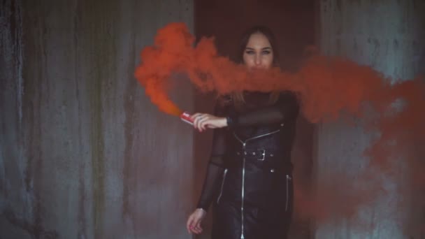 Bruut meisje met een rode rookbom in een verlaten gebouw. Model in zwart lederen kleding — Stockvideo