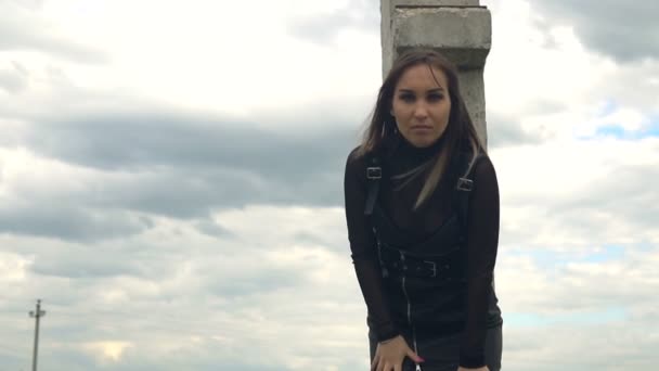 Chica sobre un fondo de nubes grises. Cabello revoloteando en el viento. Movimiento lento — Vídeos de Stock