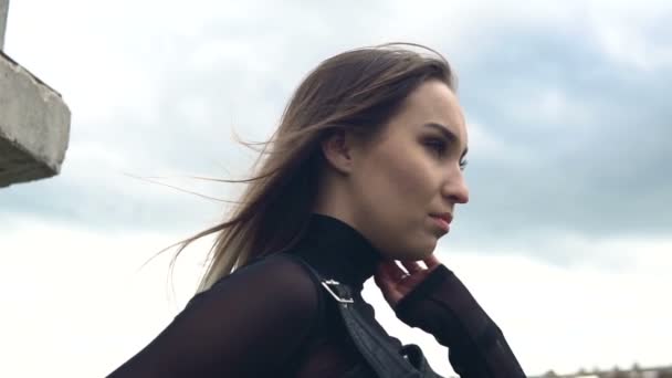 Mädchen auf einem Hintergrund grauer Wolken. Haare flattern im Wind. Zeitlupe — Stockvideo