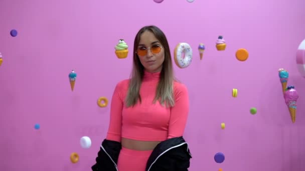 Fashionable girl in the midst of sweetly hanging in the air on a pink background — Stock Video