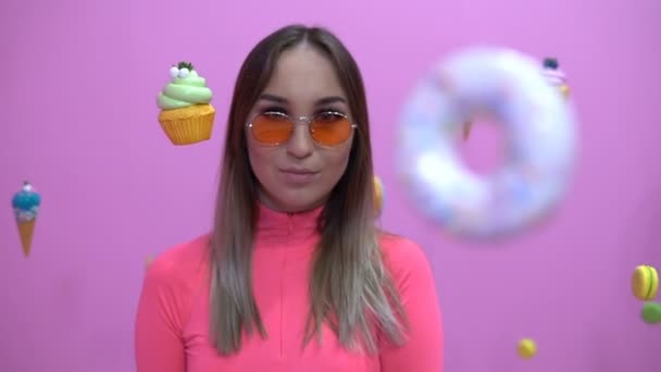 Fashionable girl in the midst of sweetly hanging in the air on a pink background — Stock Video