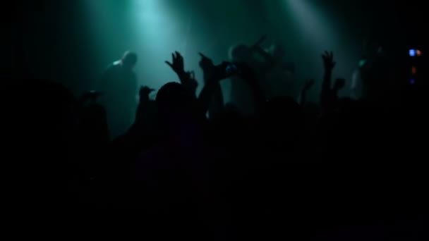 Crowd people at music concert . Cheering crowd takes pictures on a smartphone in front of bright colorful stage lights . silhouettes of concert crowd in front stage lights of bright . crowd of people — Stock Video