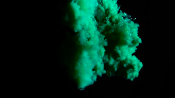 Настоящая зеленая краска падает в воду в замедленной съемке. Чернила кружатся под водой. Облако столкновения чернил изолировано на черном фоне с альфой. Закрыть вид — стоковое видео