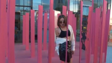 Pembe arka planda aynaların arasında dans eden bir kız. Kız şık giyinmiş.