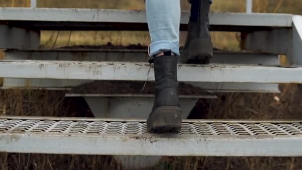 Молода жінка піднімається по сходах. Дівчина в чорних чоботях — стокове відео