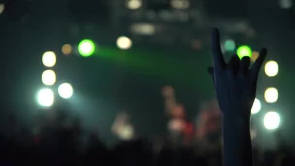 Kobieta na koncercie podniosła ręce do góry. Śmiejący się tłum przed jasnymi kolorowymi światłami sceny. Sylwetki tłumu koncertowego w przednich światłach sceny. — Wideo stockowe