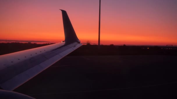 O avião está a preparar-se para descolar. A asa do avião está a tremer. Ao pôr do sol — Vídeo de Stock