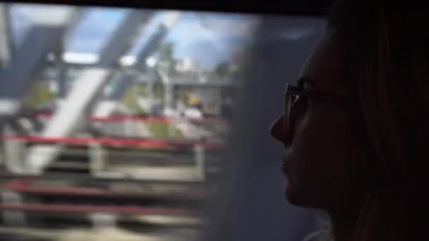 La giovane donna con gli occhiali viaggia in treno. La ragazza guarda fuori dalla finestra. — Video Stock