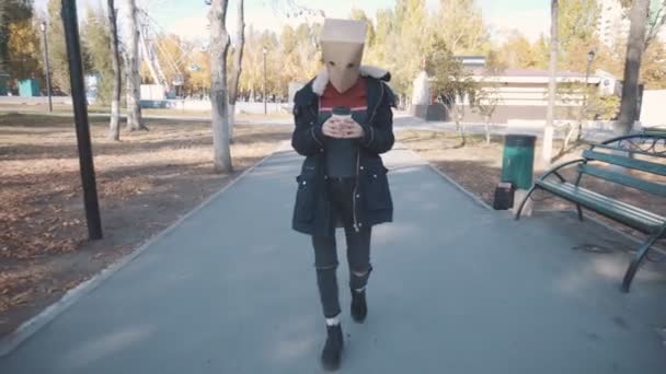 Flicka med ett paket på huvudet går med en kopp kaffe. Flicka i jacka — Stockvideo