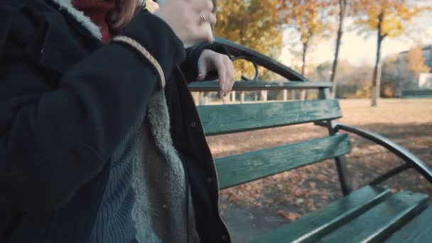 女孩在长椅上喝咖啡，特写 — 图库视频影像