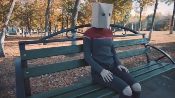 Une fille avec une meute sur la tête sur un banc dans le parc. Fille dans une veste — Video