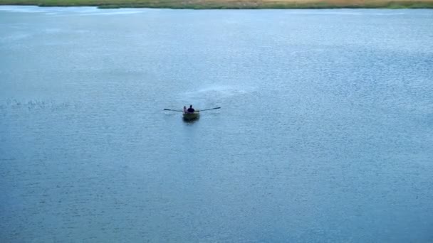 Les gens sont sur un bateau avec des rames. Bateau dans le lac bleu — Video