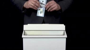 Schroeder 100 dolarlık banknotu yok etti. Takım elbiseli bir işadamı kağıt öğütücüye para atıyor.
