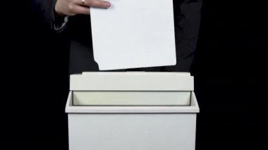 Shredder belgeleri yok ediyor. Takım elbiseli bir işadamı kağıt öğütücüsüne kağıt koyuyor.