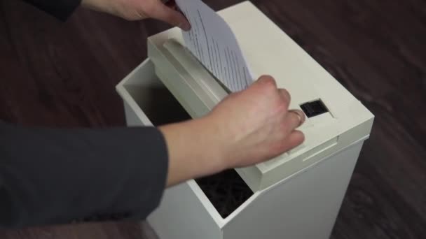 Shredder vernietigt documenten. Zakenman in pak stopt een vel papier in een papierversnipperaar — Stockvideo